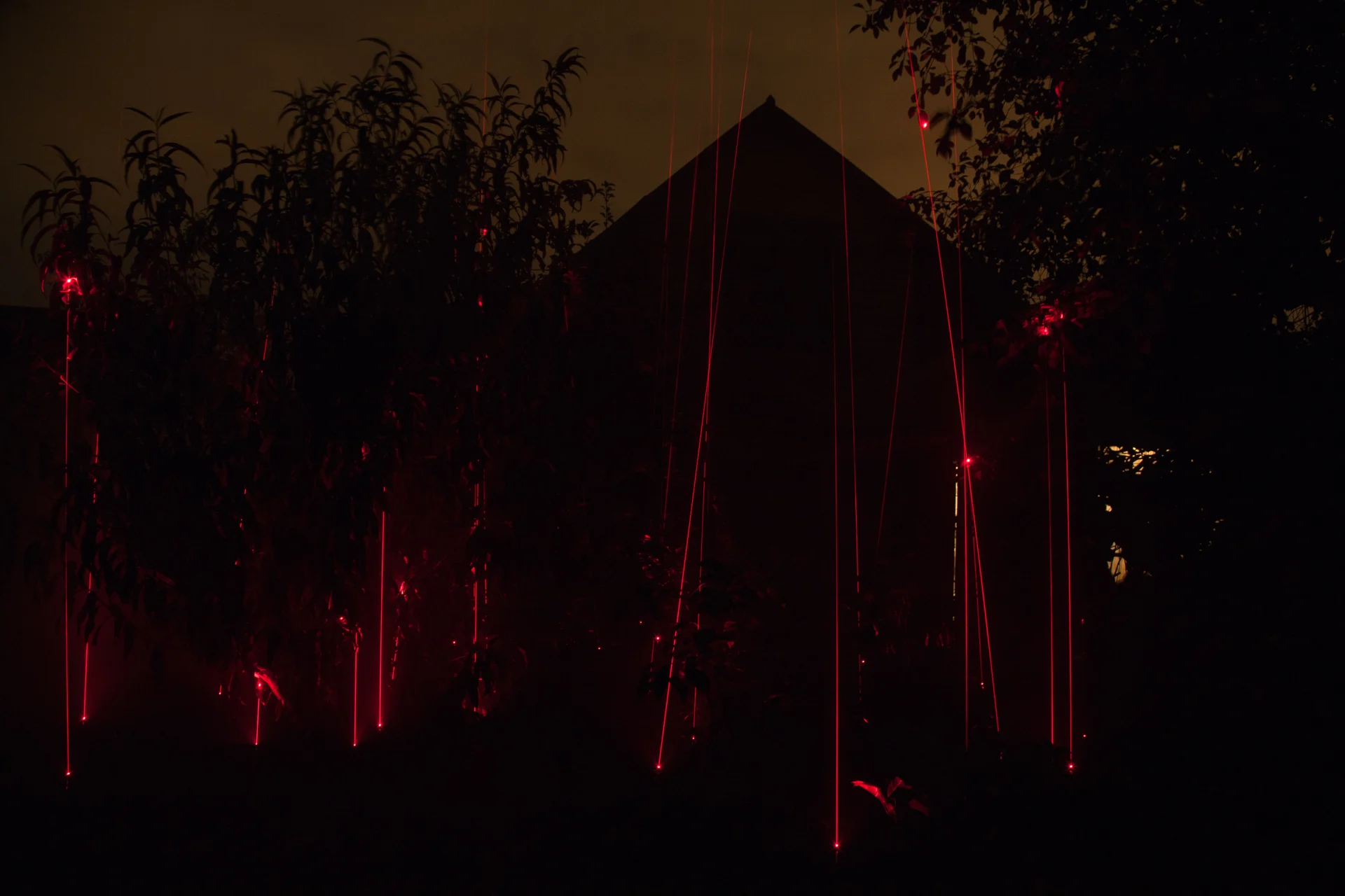 An outdoor grouping of red laser lights at night