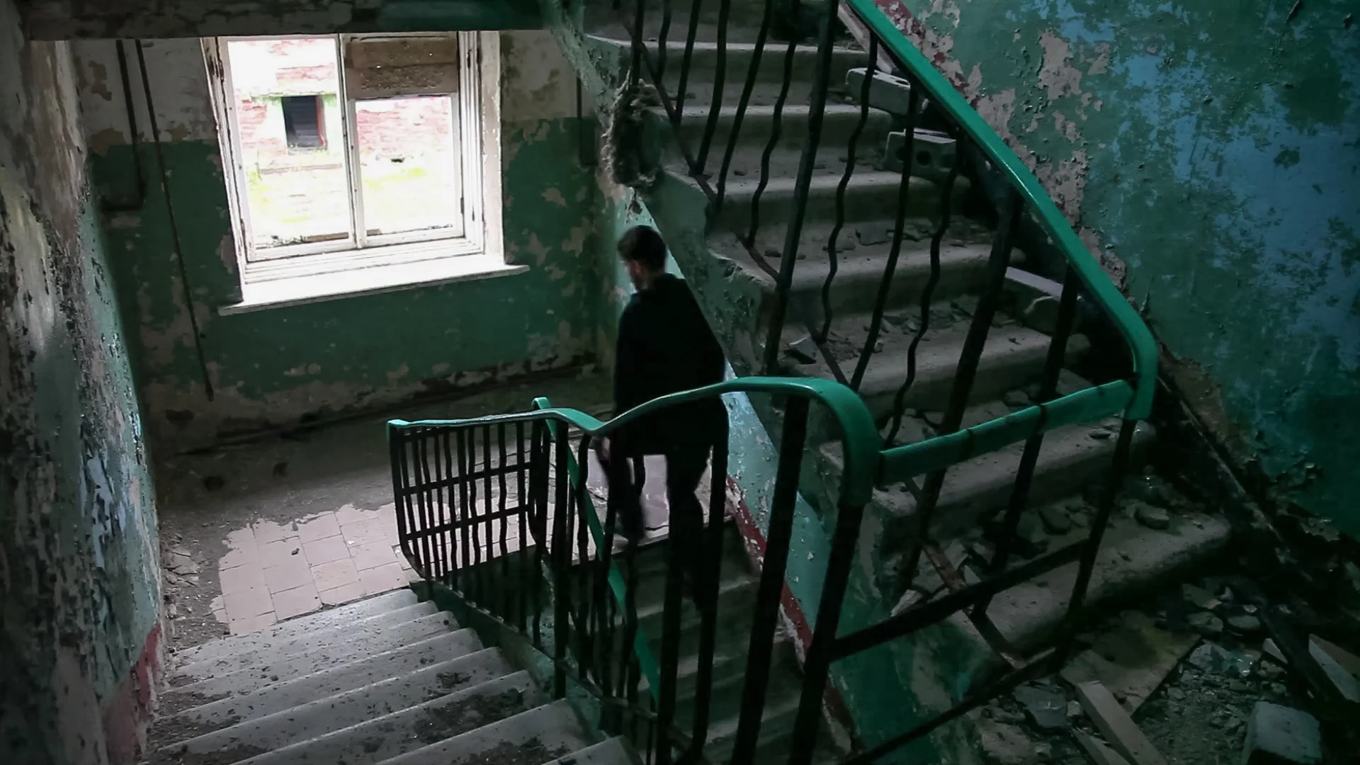 A figure moving beside a staircase inside the building