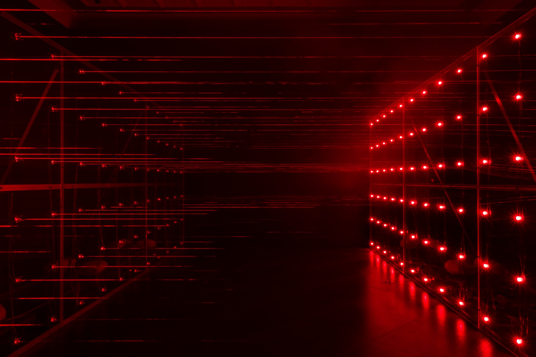 Installation view: opposing structures and a red laser field.