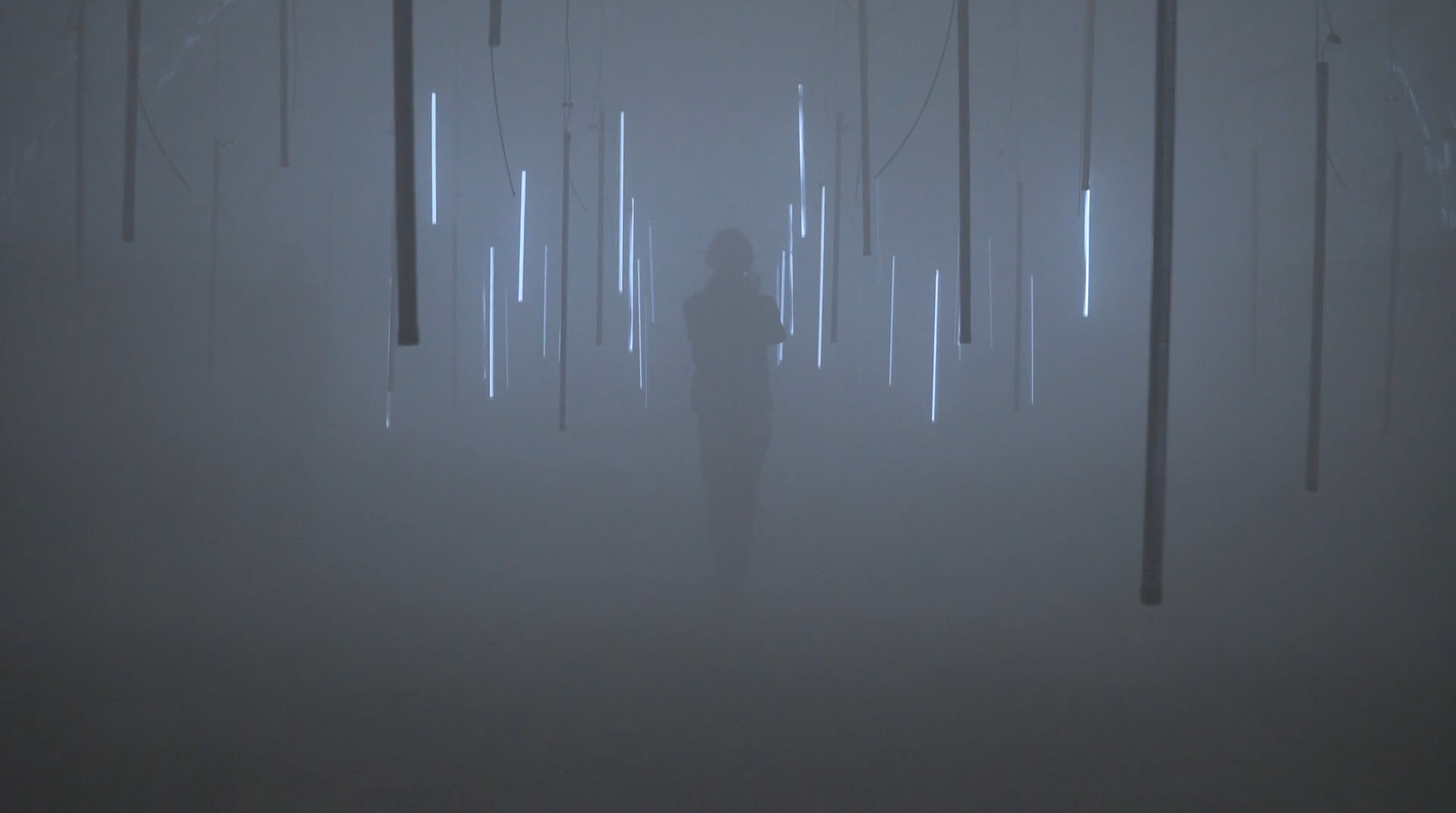 A visitor among suspended light objects in a dense, blue-grey haze.