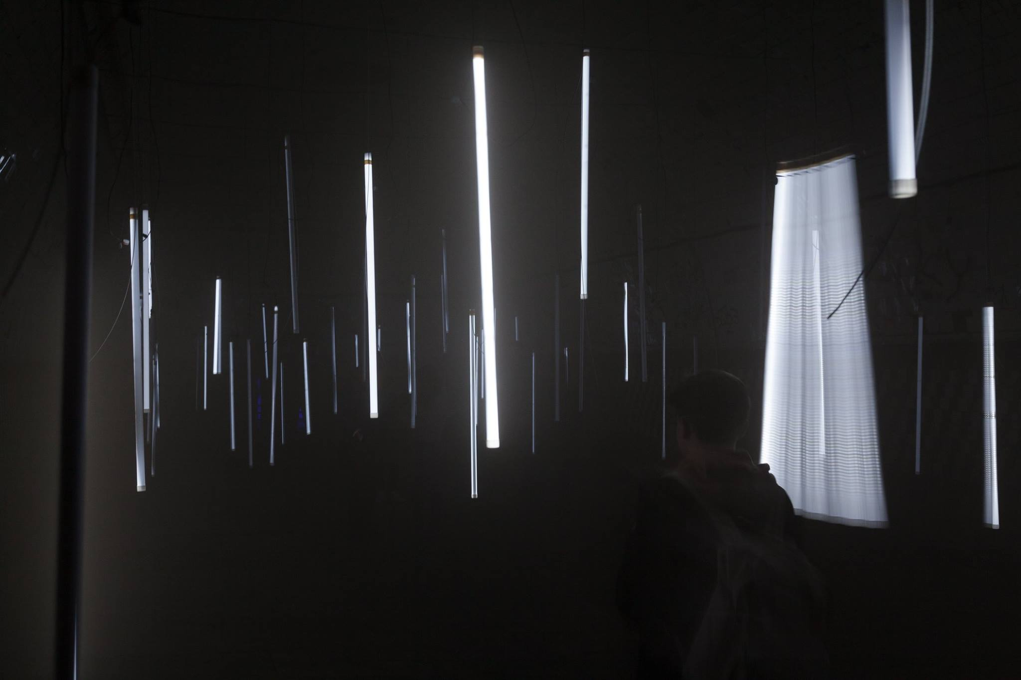 A visitor in the installation, with bright light objects and a broad motion trace on the right.